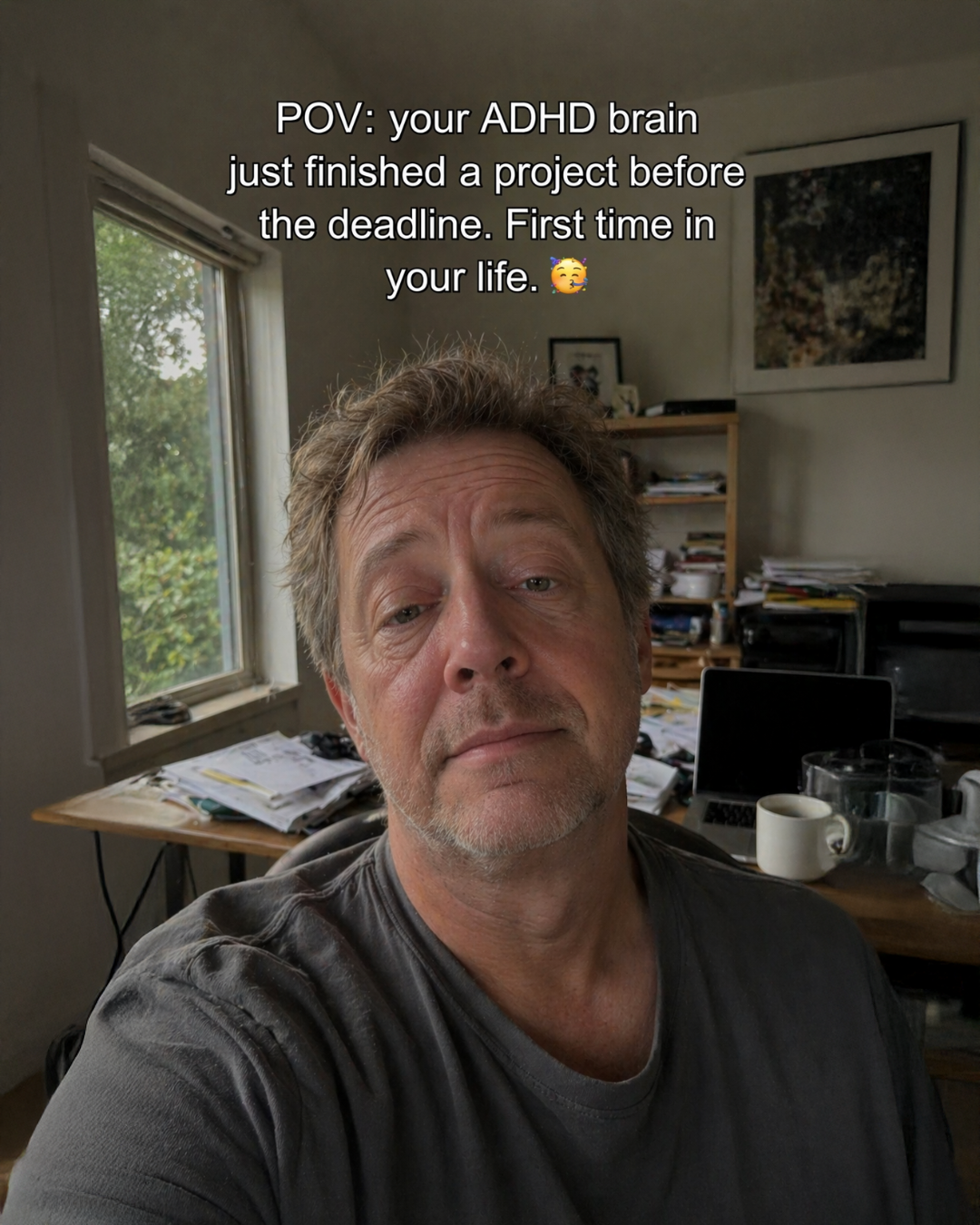 Selfie POV of a relieved man at a cluttered desk who finished a project before the deadline for the first time