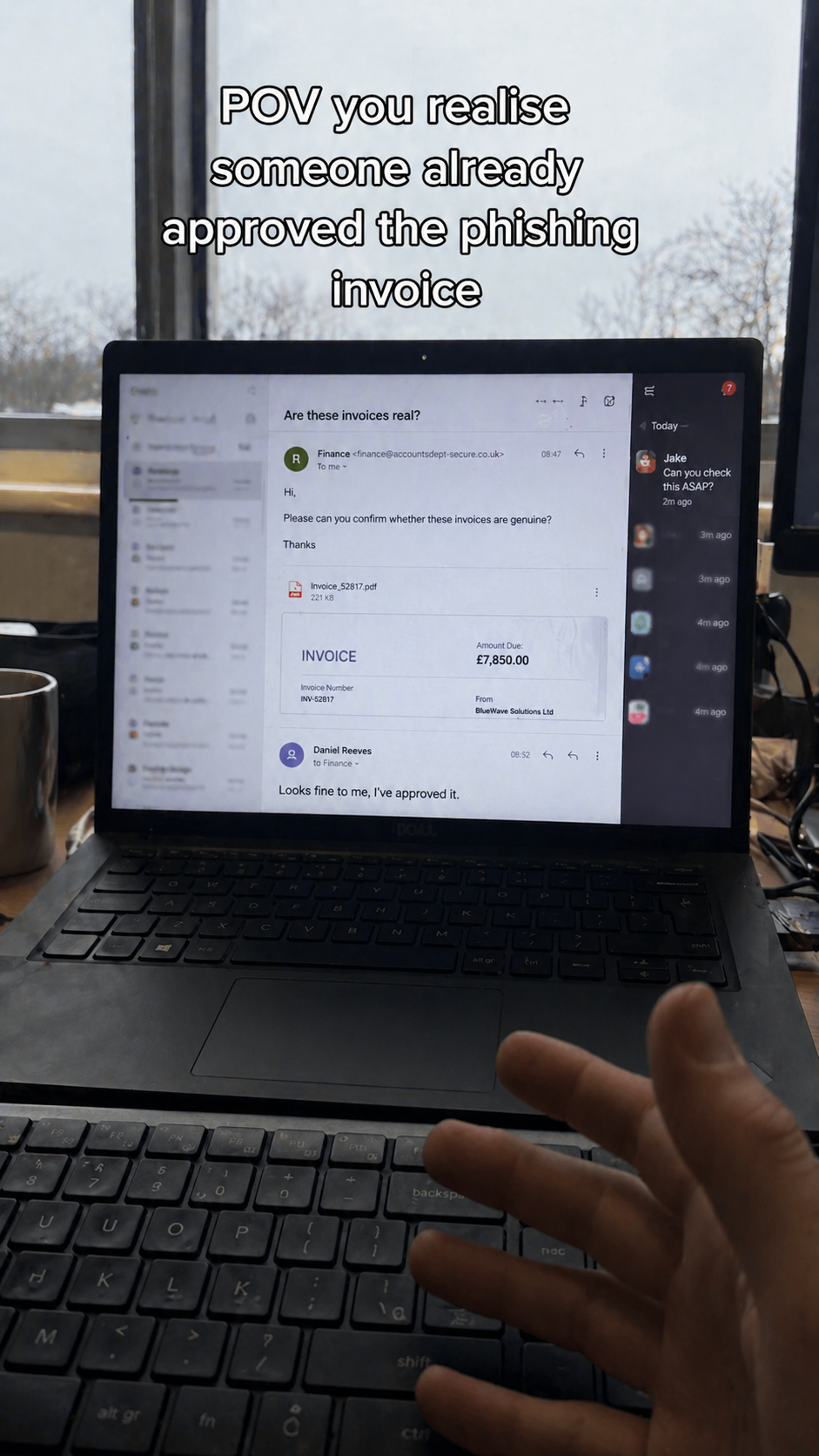 POV of a hand reaching toward a laptop showing a phishing invoice email for £7,850 that someone has already approved